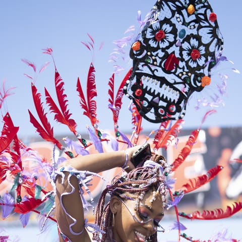 A masquerader in a crimson costume with a carved headpiece